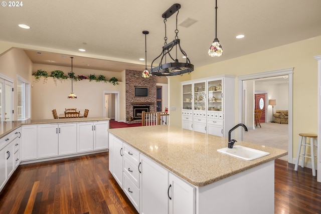 kitchen featuring white cabinets, a fireplace, sink, and decorative light fixtures