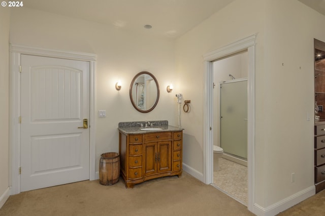 bathroom with vanity, toilet, and a shower with door