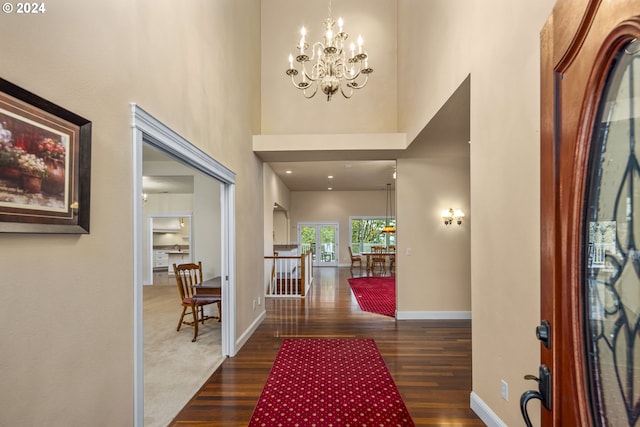 entryway with a high ceiling, dark wood-type flooring, and a chandelier