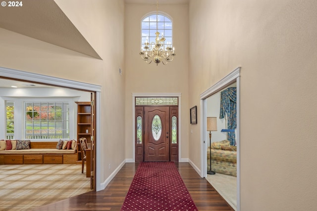 entryway featuring an inviting chandelier, a towering ceiling, and dark hardwood / wood-style flooring