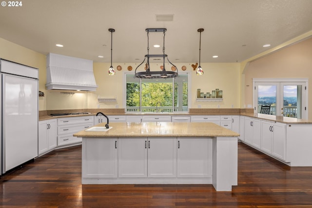 kitchen featuring premium range hood, paneled built in refrigerator, kitchen peninsula, stainless steel gas stovetop, and light stone countertops