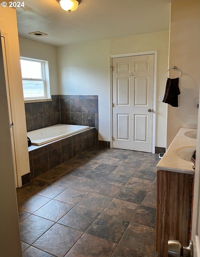 bathroom with vanity and tiled tub