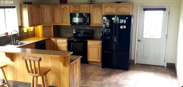 kitchen with a breakfast bar area, decorative backsplash, sink, and black appliances