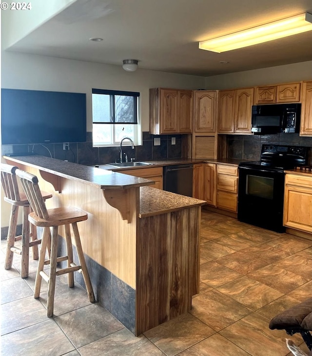 kitchen with sink, kitchen peninsula, a kitchen bar, decorative backsplash, and black appliances