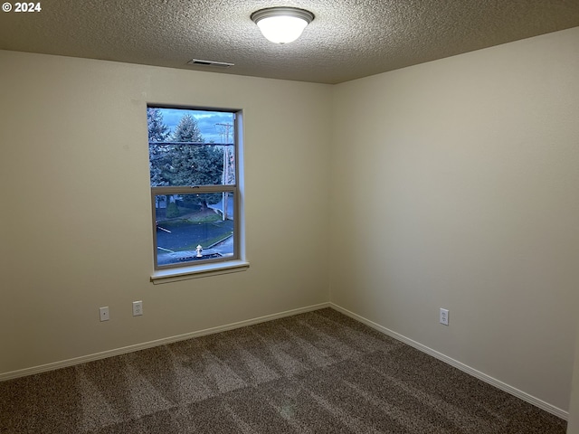 carpeted empty room with a textured ceiling