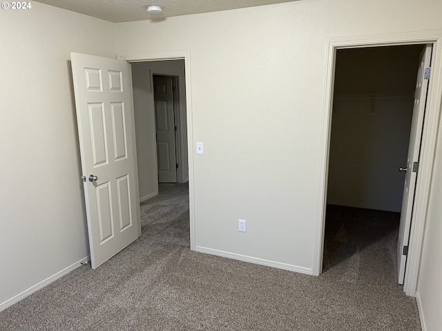 unfurnished bedroom with carpet, a walk in closet, and a closet