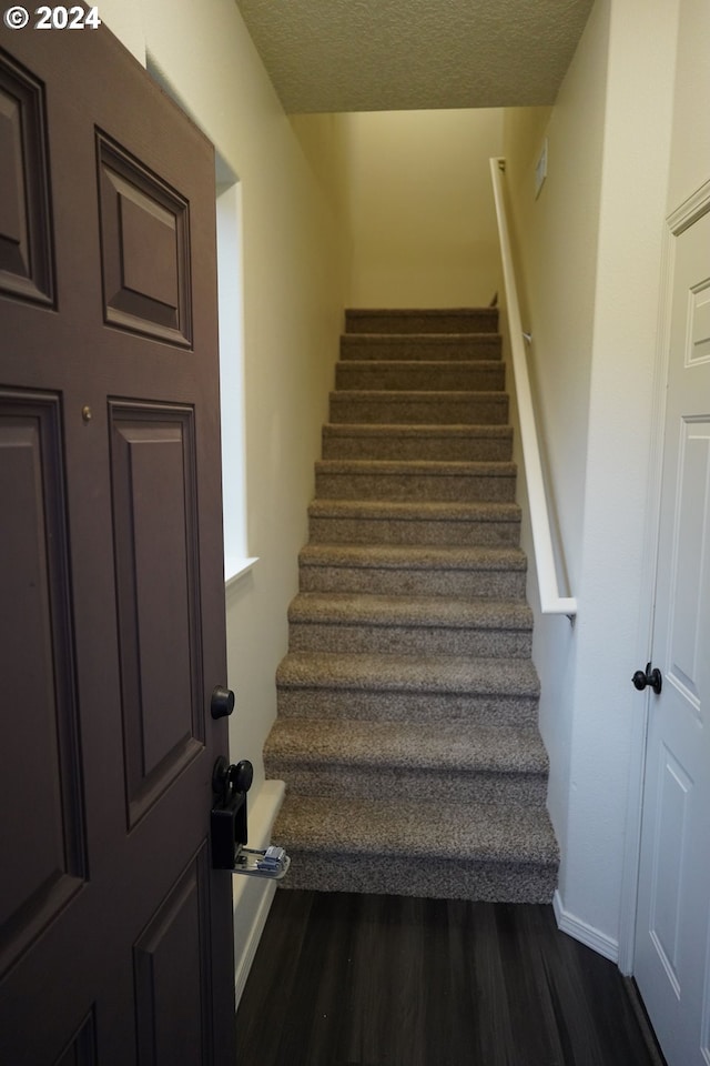 staircase featuring hardwood / wood-style floors and a textured ceiling