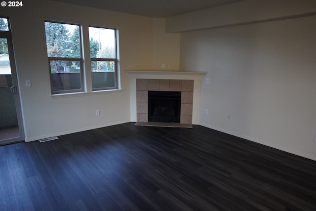 unfurnished living room featuring dark hardwood / wood-style flooring and a tile fireplace