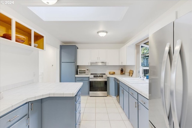 kitchen featuring tasteful backsplash, light tile patterned floors, white cabinets, sink, and stainless steel appliances