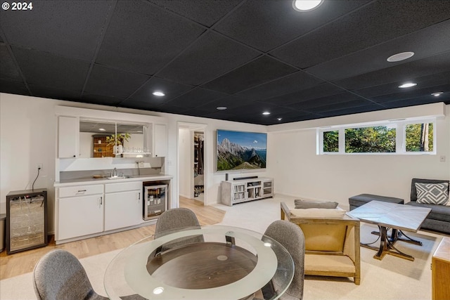 living room with light hardwood / wood-style floors, a drop ceiling, wine cooler, and wet bar