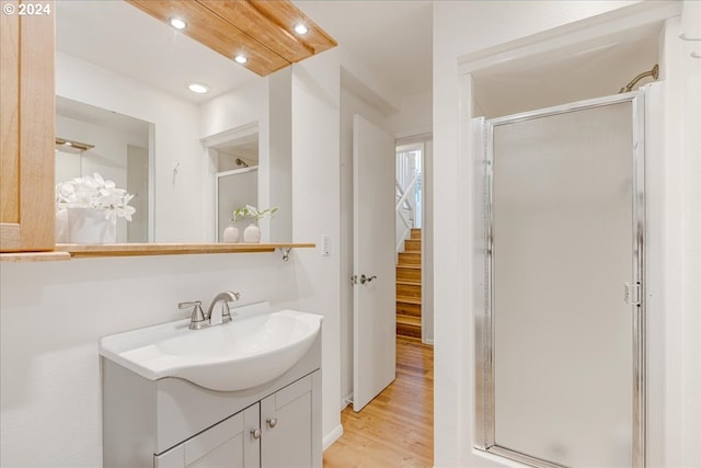 bathroom featuring vanity, a shower with shower door, and wood-type flooring