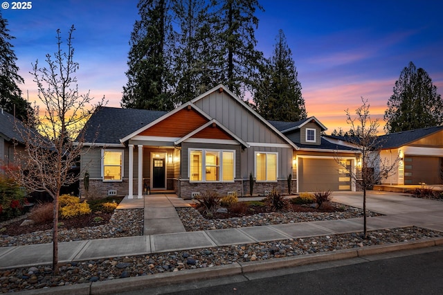 craftsman house with stone siding, board and batten siding, concrete driveway, an attached garage, and a shingled roof