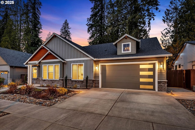 craftsman inspired home featuring fence, driveway, a garage, stone siding, and board and batten siding