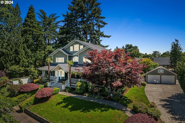 view of front of home featuring an outbuilding, a porch, a garage, and a front yard