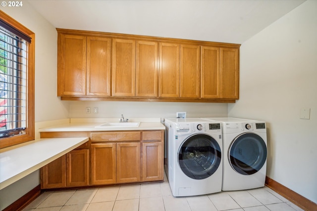 laundry room with cabinets, light tile patterned floors, washing machine and dryer, and sink