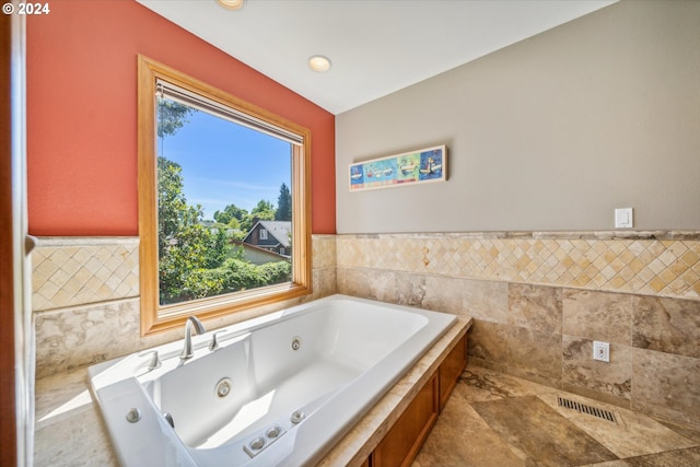 bathroom featuring a wealth of natural light, a bathing tub, and tile walls