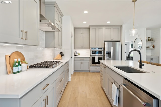 kitchen with gray cabinetry, sink, light hardwood / wood-style floors, stainless steel appliances, and decorative light fixtures