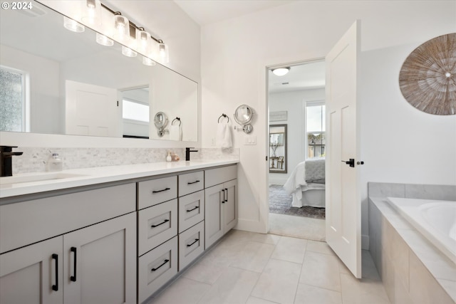 bathroom featuring vanity, tile patterned flooring, and tiled tub