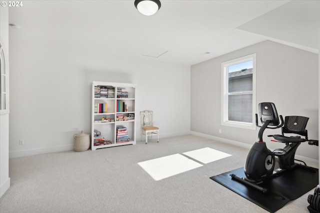 exercise area with vaulted ceiling and light colored carpet