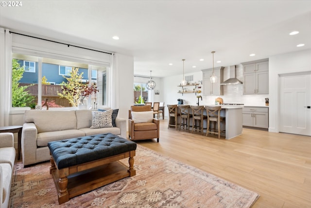 living room with a notable chandelier, light hardwood / wood-style floors, a healthy amount of sunlight, and sink