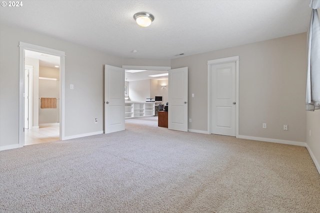 unfurnished bedroom featuring light colored carpet and a textured ceiling