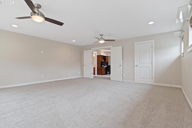 unfurnished living room with light colored carpet and ceiling fan