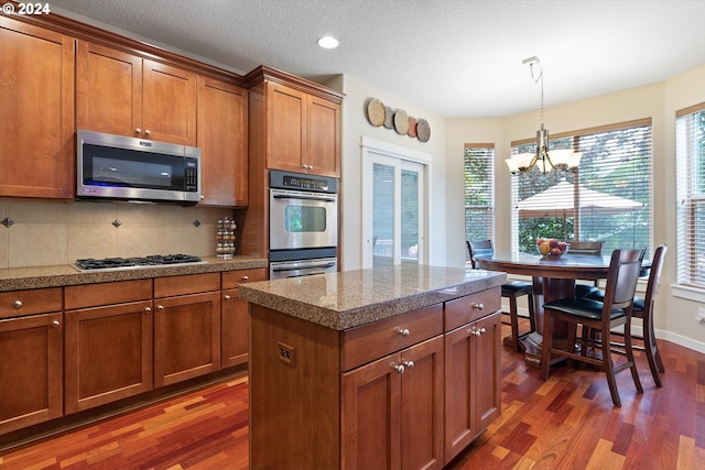 kitchen featuring stainless steel appliances, tasteful backsplash, dark wood-type flooring, and an inviting chandelier