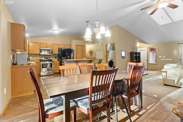 dining space featuring ceiling fan with notable chandelier, a textured ceiling, light hardwood / wood-style flooring, and vaulted ceiling