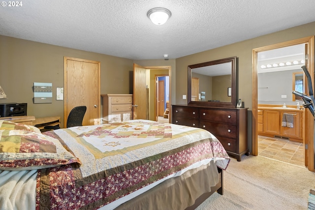 bedroom featuring ensuite bath, light carpet, a textured ceiling, and sink