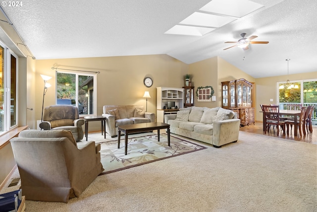 living room with ceiling fan, a textured ceiling, light carpet, and lofted ceiling with skylight