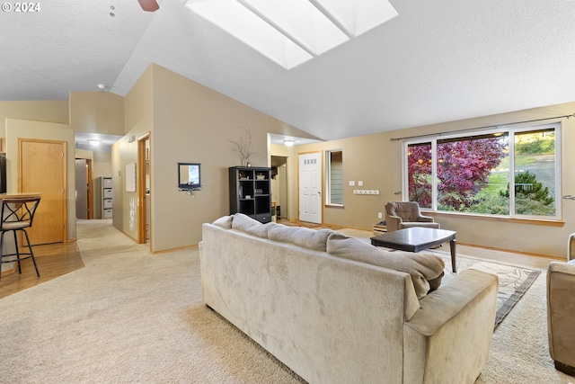 carpeted living room with ceiling fan, a textured ceiling, and lofted ceiling with skylight