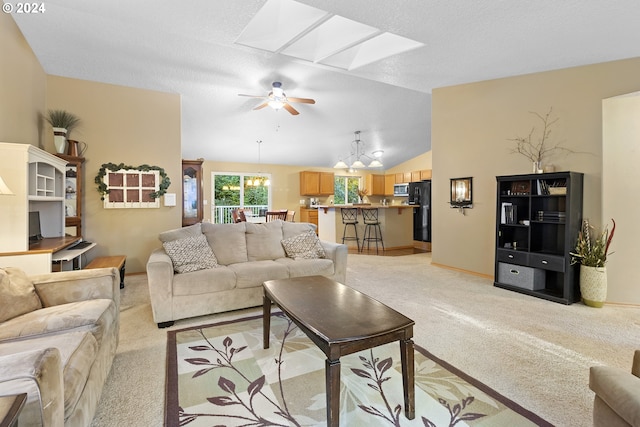 living room with light colored carpet, ceiling fan with notable chandelier, a textured ceiling, and lofted ceiling with skylight