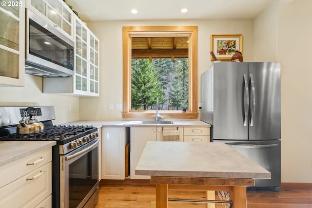 kitchen featuring recessed lighting, a sink, light countertops, appliances with stainless steel finishes, and light wood-type flooring