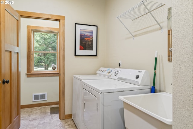 laundry room featuring visible vents, a sink, baseboards, laundry area, and separate washer and dryer