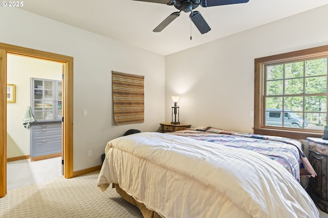 bedroom with light carpet, ceiling fan, a walk in closet, and baseboards