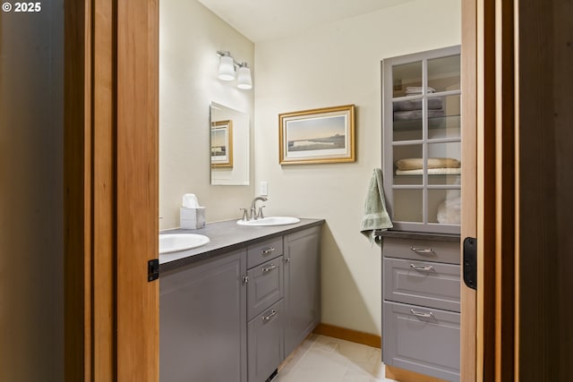 bathroom with double vanity, tile patterned floors, baseboards, and a sink