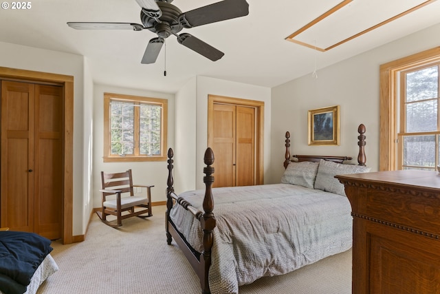 bedroom with baseboards, light carpet, attic access, and a ceiling fan