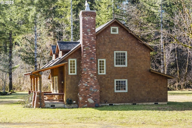 view of side of home with a wooded view, a porch, a yard, a chimney, and crawl space