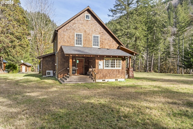 view of front of home with a front yard, a wooded view, an outdoor structure, crawl space, and a storage shed