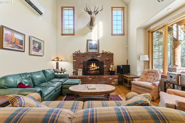 living area with a fireplace, a wall mounted AC, a high ceiling, and wood finished floors