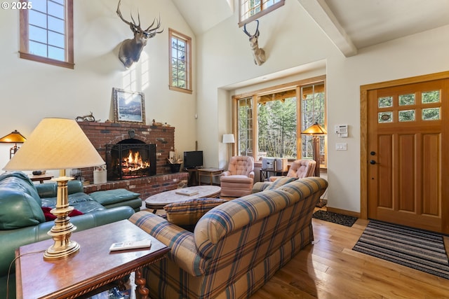 living room with plenty of natural light, a fireplace, a high ceiling, and wood-type flooring