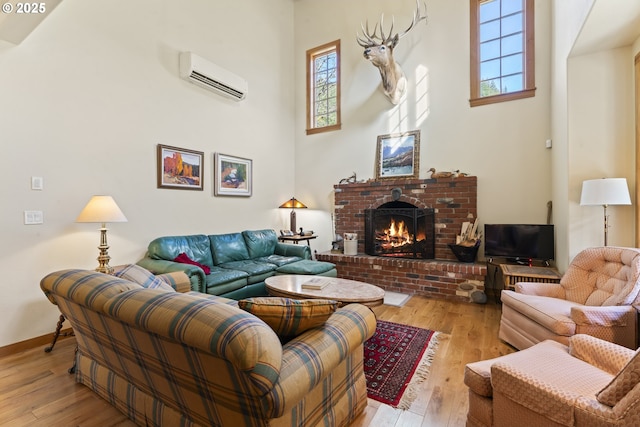 living room with a high ceiling, an AC wall unit, a fireplace, and hardwood / wood-style flooring