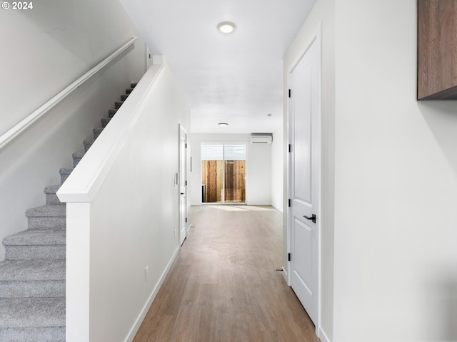 corridor featuring a wall mounted air conditioner and hardwood / wood-style flooring