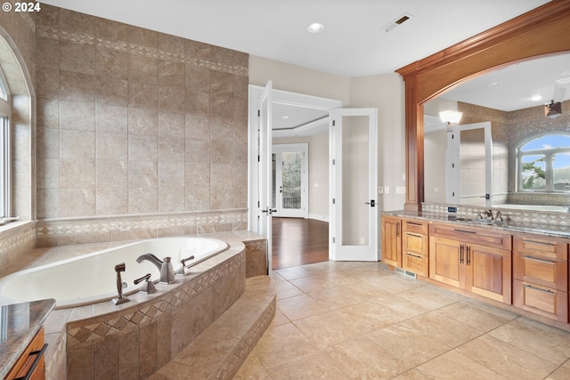 bathroom with vanity, tile walls, hardwood / wood-style flooring, tasteful backsplash, and tiled bath