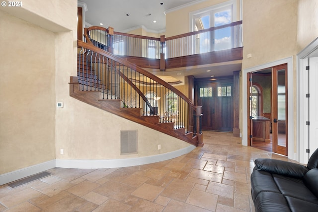 tiled foyer with a towering ceiling and crown molding