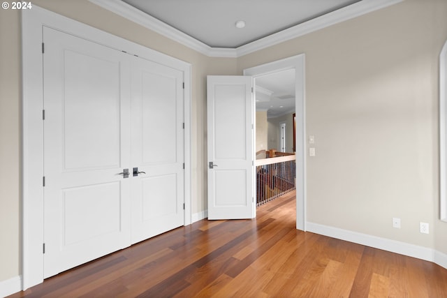 unfurnished bedroom featuring dark hardwood / wood-style flooring, crown molding, and a closet