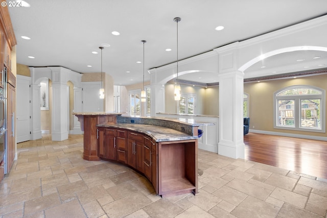 kitchen featuring a kitchen island, light tile flooring, decorative columns, crown molding, and pendant lighting