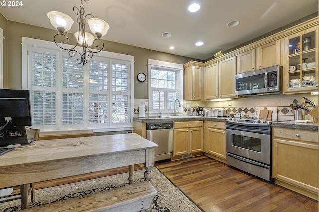 kitchen featuring a chandelier, appliances with stainless steel finishes, dark wood-type flooring, tasteful backsplash, and sink