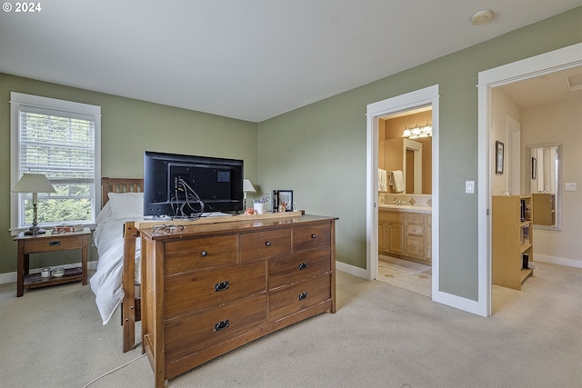 bedroom featuring an inviting chandelier, light colored carpet, and ensuite bathroom