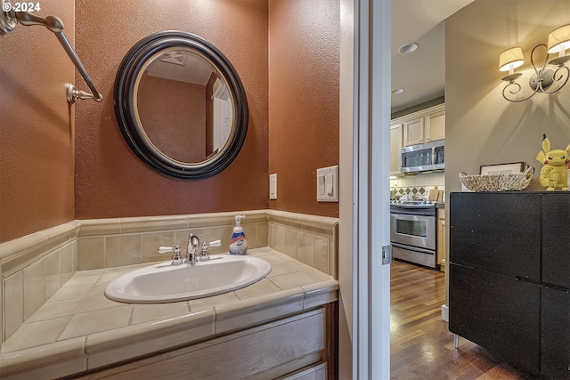 bathroom with vanity, decorative backsplash, and hardwood / wood-style floors